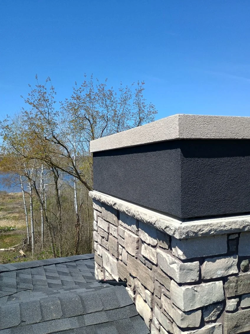 Chimney chase with dark stucco over stone veneer