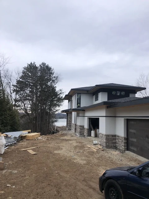 New custom home with white stucco and stone veneer base