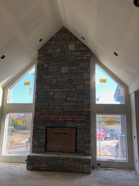 Floor-to-ceiling stone veneer fireplace in vaulted room