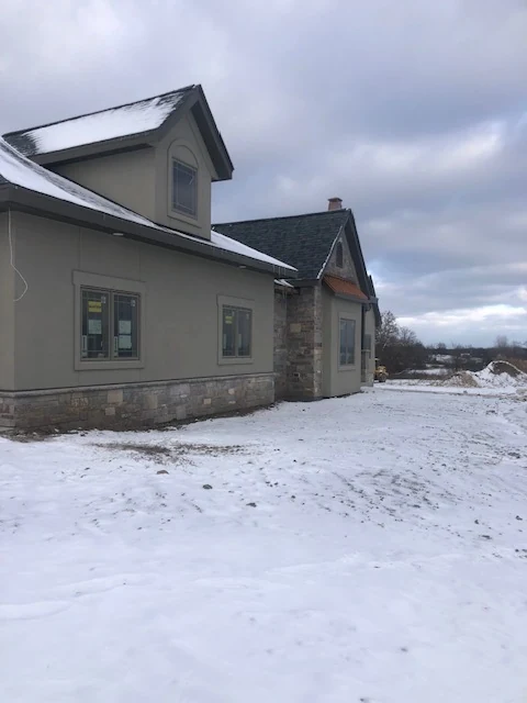 Home exterior with tan stucco and stone veneer wainscot